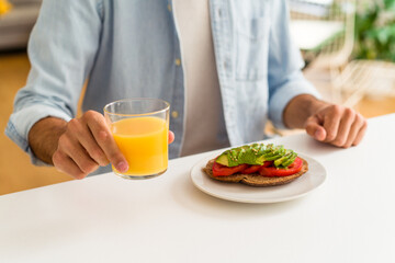 Obraz na płótnie Canvas Young mixed race man having breakfast in his kitchen