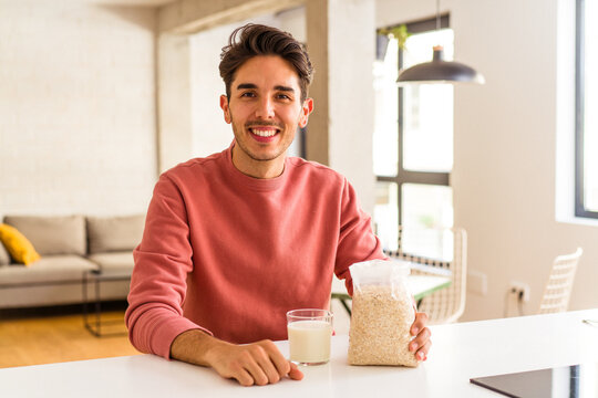 Young Mixed Race Man Eating Oatmeal And Milk For Breakfast In His Kitchen