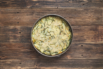 Zucchini pie, baked with parmesan, eggs and herbs in baking dish on the wooden background, top view with copy space