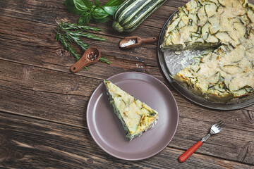 Homemade zucchini pie, baked with parmesan, eggs and herbs on the wooden background, top view