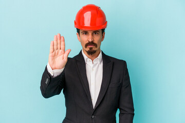 Young architect caucasian man isolated on blue background standing with outstretched hand showing stop sign, preventing you.