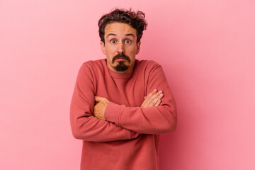 Obraz premium Young caucasian man isolated on pink background shrugs shoulders and open eyes confused.