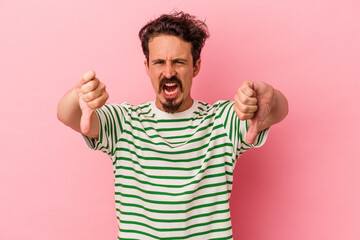 Fototapeta premium Young caucasian man isolated on pink background showing thumb down and expressing dislike.