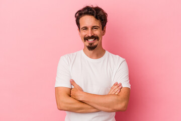 Young caucasian man isolated on pink background who feels confident, crossing arms with determination.