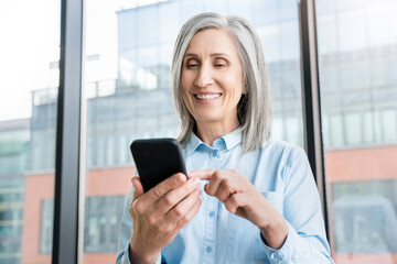 Close up of senior businesswoman who is using a smartphone in an office.