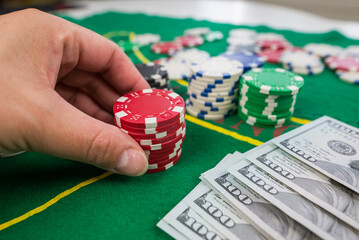 Naklejka premium close-up of a human hand with peoker chips on a green casino table. gamble.