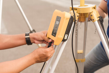 A surveyor setting up a wireless data transceiver. Surveying equipment used in the field. - obrazy, fototapety, plakaty