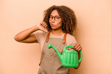 Young gardener African American woman holding irrigation isolated on beige background feels proud and self confident, example to follow.
