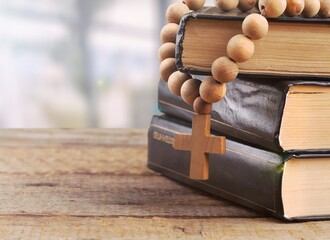 Holy Bible with wooden cross on light room background