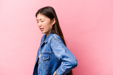 Young Chinese woman isolated on pink background suffering a back pain.