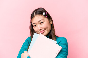 Young asian student woman holding books isolated on pink background