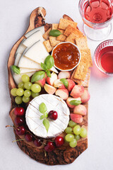 Healthy mediterranean cheese and fruits board with rose wine on light background