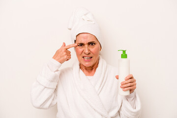 Middle age caucasian woman wearing a bathrobe holding body cream isolated on white background showing a disappointment gesture with forefinger.