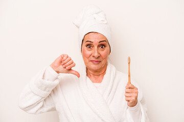 Middle age caucasian woman wearing a bathrobe holding toothbrush isolated on white background showing a dislike gesture, thumbs down. Disagreement concept.