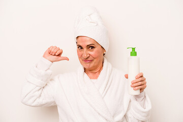 Middle age caucasian woman wearing a bathrobe holding body cream isolated on white background feels proud and self confident, example to follow.