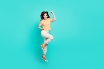 Full body photo of overjoyed satisfied lady scream yeah raise fists jump isolated on turquoise color background