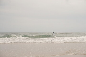 Fototapeta na wymiar Man in Black Wetsuit on Surfboard in Surf on Sunny Day at Hatteras
