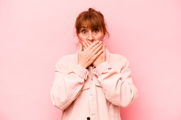 Middle age caucasian woman isolated on pink background covering mouth with hands looking worried.