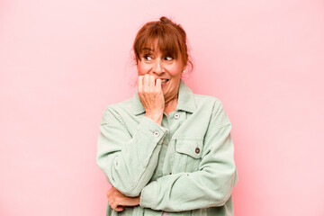 Middle age caucasian woman isolated on pink background biting fingernails, nervous and very anxious.