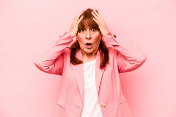 Middle age caucasian woman isolated on pink background being shocked, she has remembered important meeting.