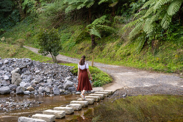 Woman walk on stepping stones across the river