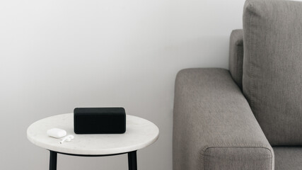 Portable music speaker with earphones on table near couch