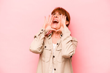 Middle age caucasian woman isolated on pink background shouting excited to front.