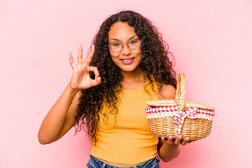 Young hispanic woman doing a picnic isolated on beige background cheerful and confident showing ok gesture.