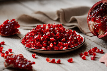 ripe peeled pomegranate on a wooden background, pomegranate seeds on a plate