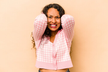 Young hispanic woman isolated on beige background screaming with rage.