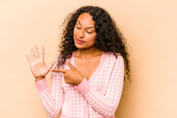 Young hispanic woman isolated on beige background smiling cheerful showing number five with fingers.