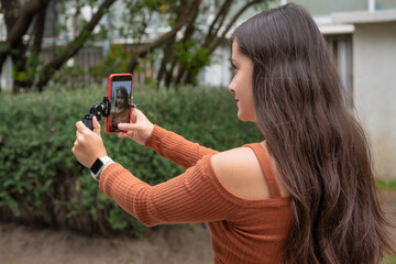 Young woman making video vlog with smartphone and gimbal stabilizer outdoor, vlogging in the streets