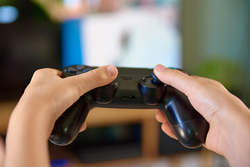 Boy playing video game on console with joyctick gamepad in his hand, Online entertainment and leisure activity, Gambling addiction