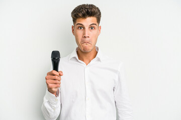 Young singer caucasian man isolated on white background shrugs shoulders and open eyes confused.
