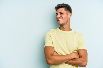Obraz premium Young caucasian man isolated on blue background smiling confident with crossed arms.