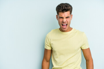 Fototapeta premium Young caucasian man isolated on blue background shouting very angry, rage concept, frustrated.