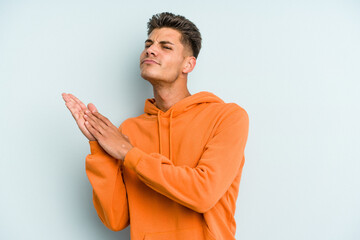 Young caucasian man isolated on blue background feeling energetic and comfortable, rubbing hands confident.