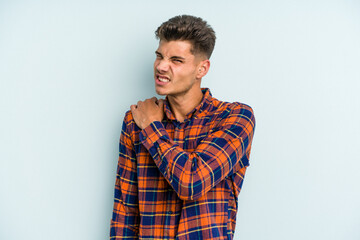 Young caucasian man isolated on blue background having a shoulder pain.