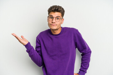 Young caucasian man isolated on white background doubting and shrugging shoulders in questioning...