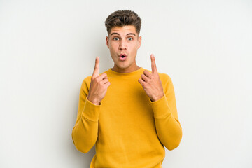 Young caucasian man isolated on white background pointing upside with opened mouth.