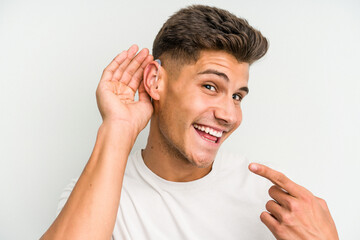 Young caucasian man wearing a hearing aid isolated on white background