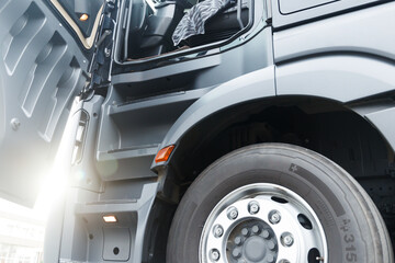 Bottom-up view of the open door of the truck cab. Bright sun in the gap between the door and the car body. Truck cab steps close up. The concept of cargo transportation.
