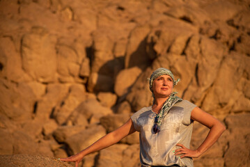Tourist woman in an arafitka on the background of a rock in the desert. Holidays