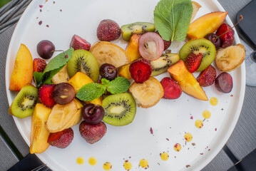 Fruit plate. Kiwi, bananas, cherries, strawberries and peaches on a plate