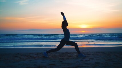 Fototapeta na wymiar Silhouette Woman practice yoga warrior pose to meditation with summer vacation beach happiness and relaxation. Calm female exercise with yoga meditate ocean beach with sunset golden time.