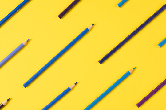 Imagine of crayons of different shades of blue on yellow background