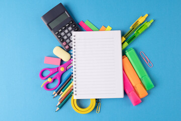 Image of various office supplies, pens and notebook on blue background