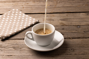 Image of white cup of coffee with milk and tea towel on wooden background