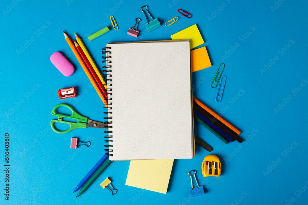 Poster composition of notebook with copy space and school tools on blue surface