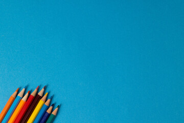 Composition of colorful crayons on blue surface with copy space